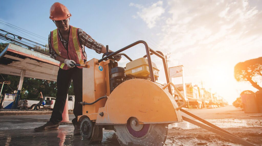 Man in PPE cutting concrete outdoors