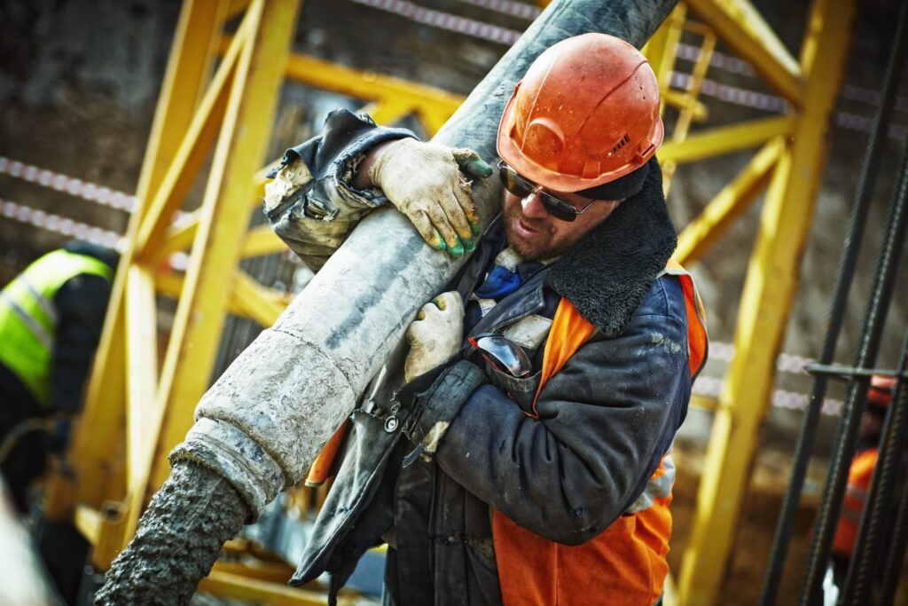 Man on a construction site pouring concrete through a tube held on his shoulder