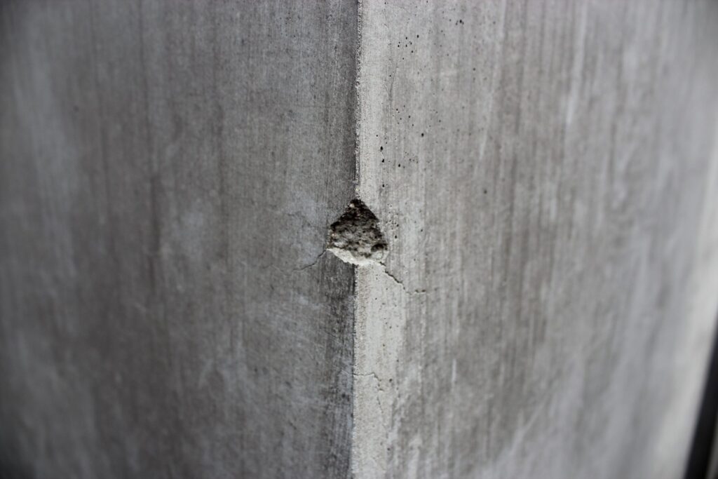 the corner of a gray concrete pillar with some material chipped off