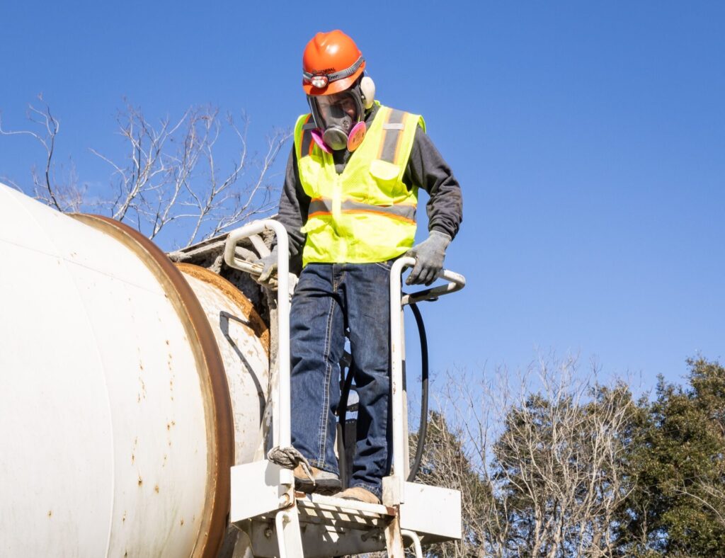 a man standing on a ladder on a cement mixer