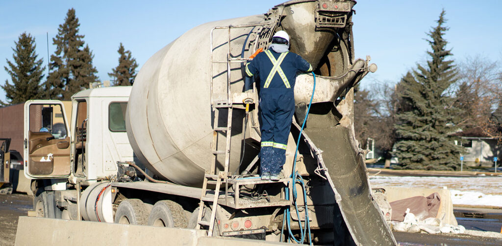 Man on ladder aiding with pour from a redi mix concrete truck