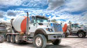 ready mix trucks in parking lot against a blue cloudy sky