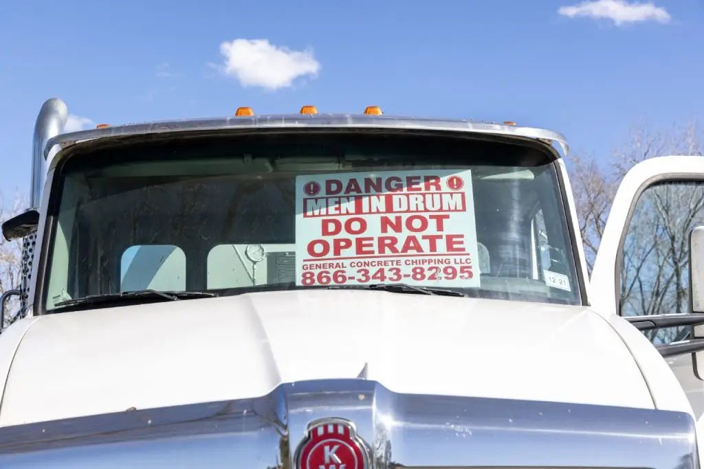 Ready mix truck with “Danger, men in drum, do not operate” sign displayed in windshield