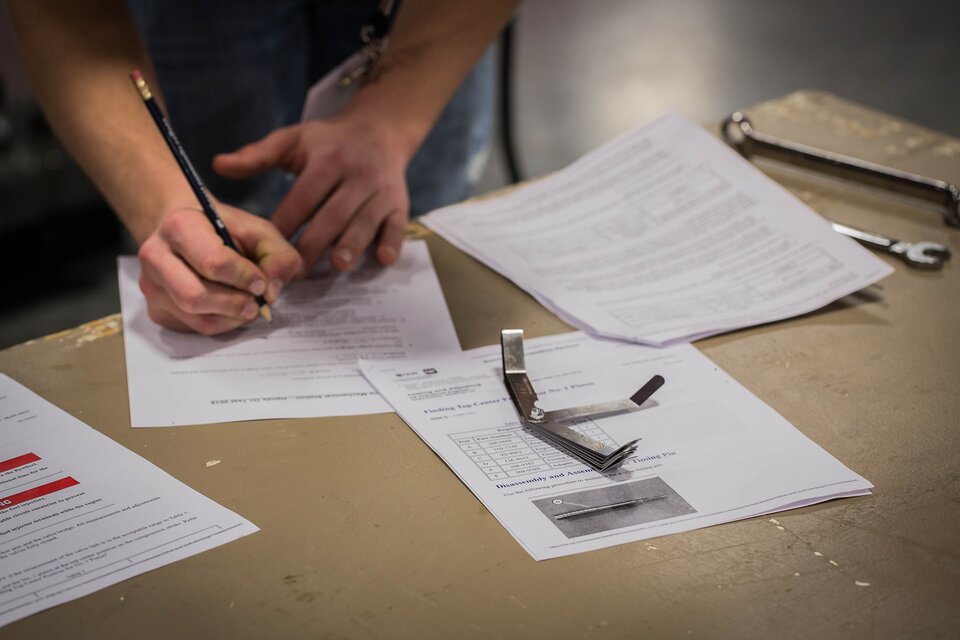 Man filling out paperwork spread out across a wooden table