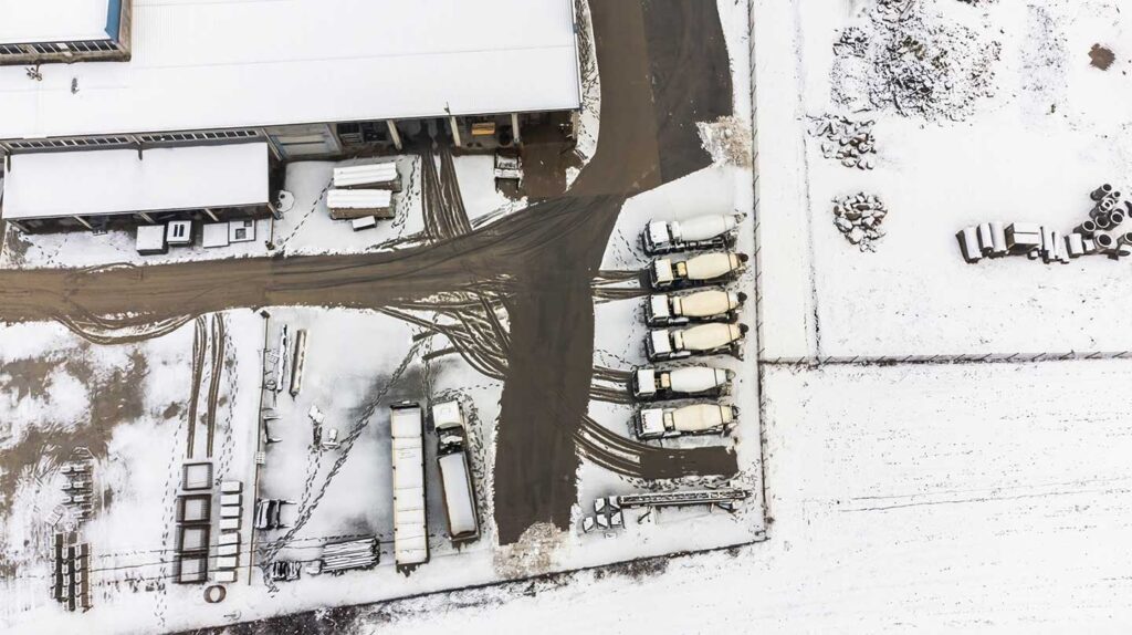 Overhead view of ready mix concrete trucks parked on snowy site