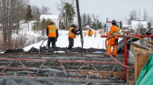 Construction crew in PPE pouring concrete on snowy site