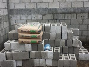 Bagged cement sitting on pile of concrete blocks in front of gray concrete wall