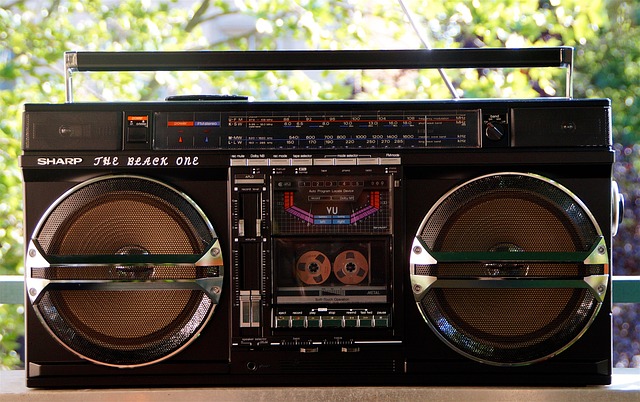 black boombox sitting on outdoor table in front of trees