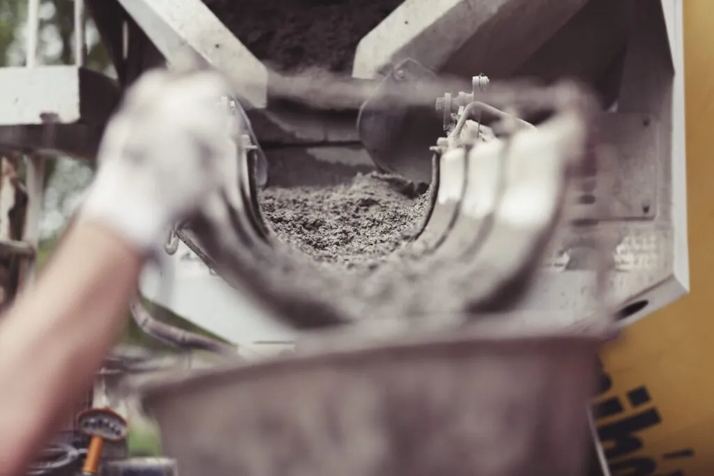 Man helping concrete pour from a ready mix truck drum