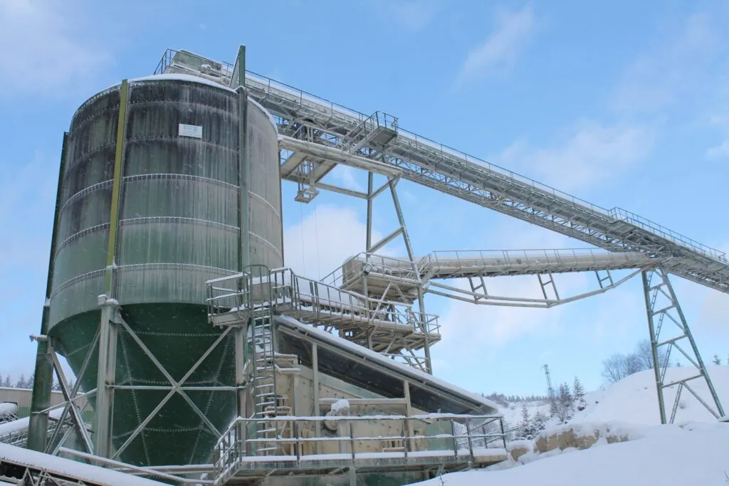 Cement silo amid snow and ice against a blue sky with clouds