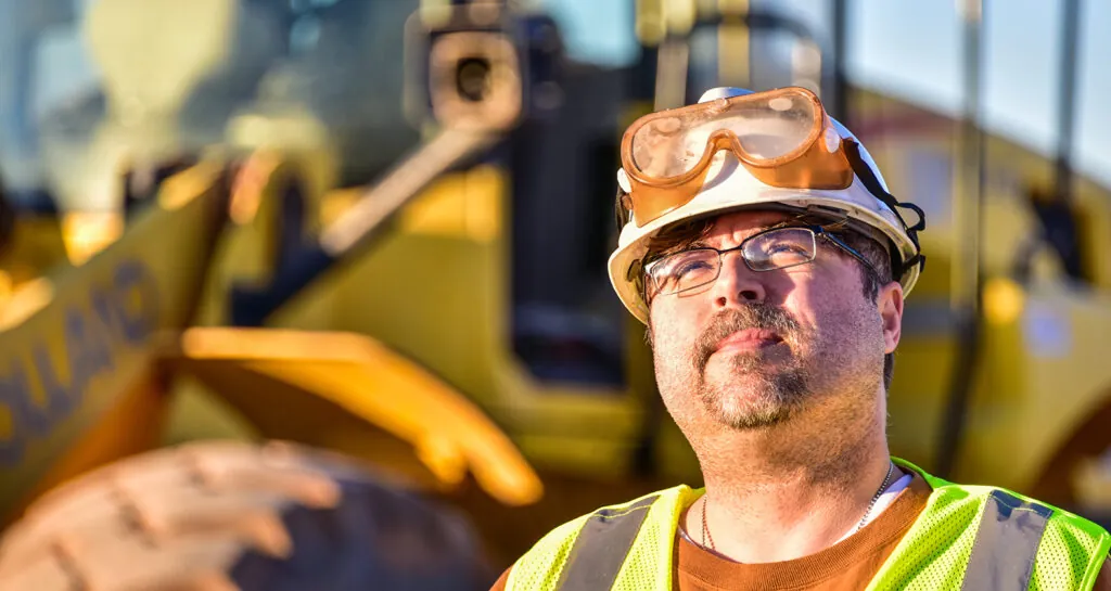 Man in personal protective equipment looking into the sky on an industrial construction site