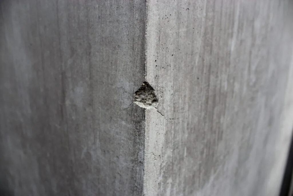 the corner of a gray concrete pillar with some material chipped off
