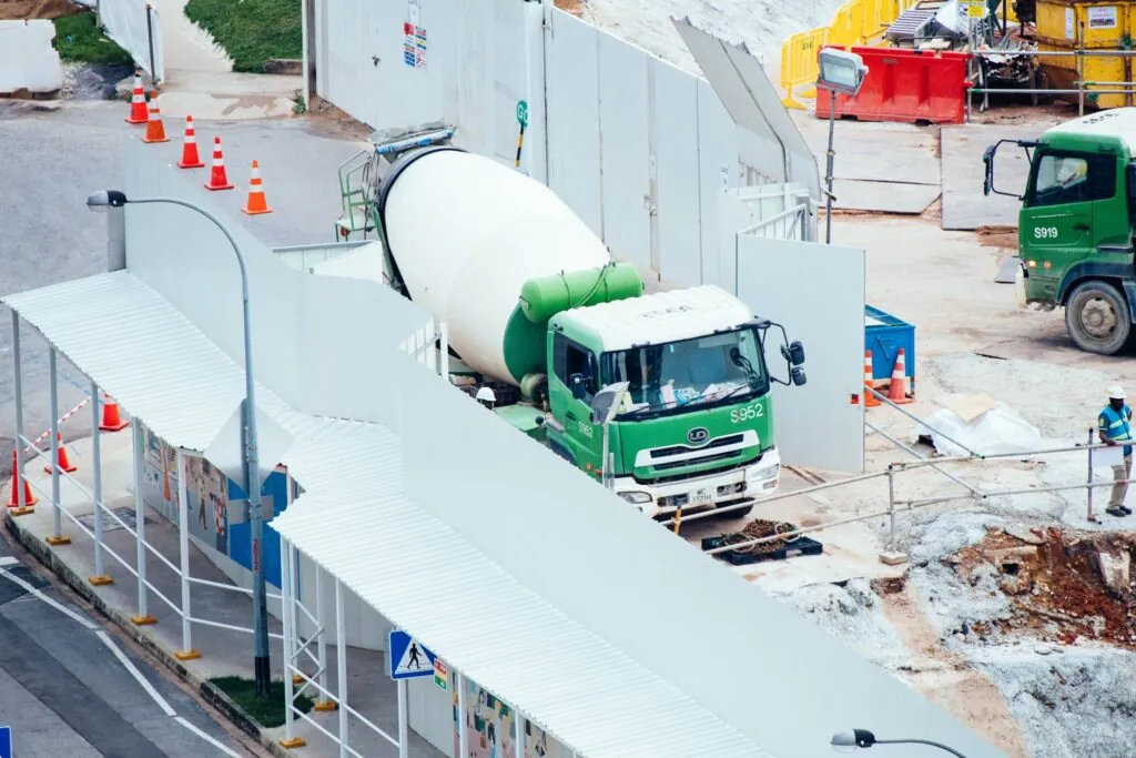 Green and white ready mix truck and concrete mixing drum on a city job site