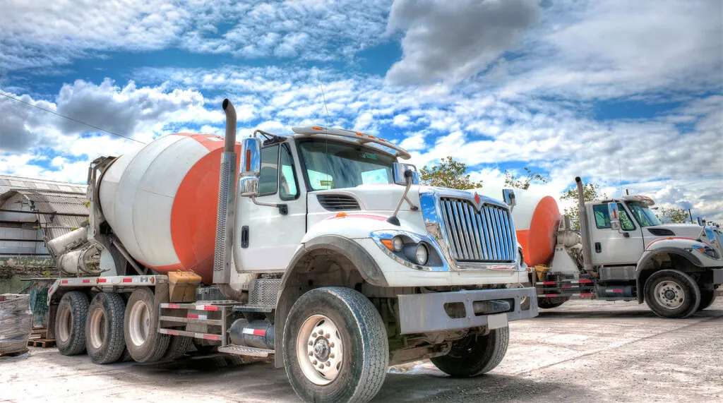 ready mix trucks in parking lot against a blue cloudy sky